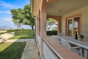 A balcony with a table and chairs, overlooking a body of water and greenery. - Holiday Home Maria with Private Beach Access (Vir)