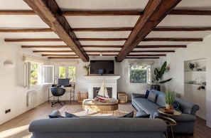 Ein Wohnzimmer mit Kamin, Sofa, Fernseher und Bücherregal.