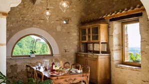 A rustic dining area with a stone wall, wooden furniture, and a view of greenery. - Maison de la Combe charming barn with pool and valley views (Laparade)