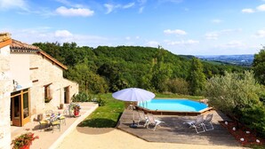 A house with a swimming pool, outdoor seating, and a view of a forested hill. - Maison de la Combe charming barn with pool and valley views (Laparade)