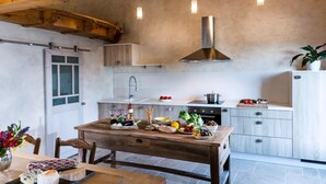 A kitchen with wooden beams, a central island with food, a stove, and a sink. - Maison de la Combe charming barn with pool and valley views (Laparade)