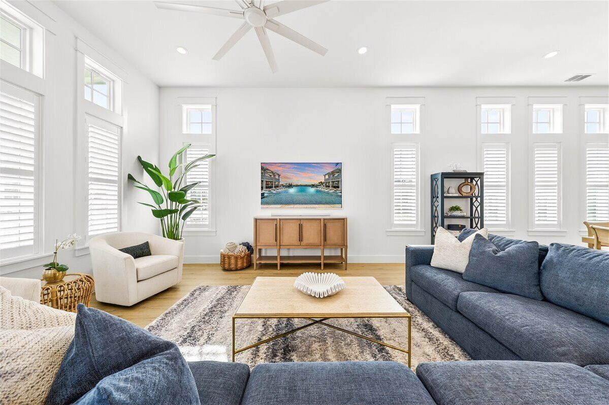 A spacious living room with a large sofa, a coffee table, a white armchair, a wooden cabinet, and a painting on the wall.