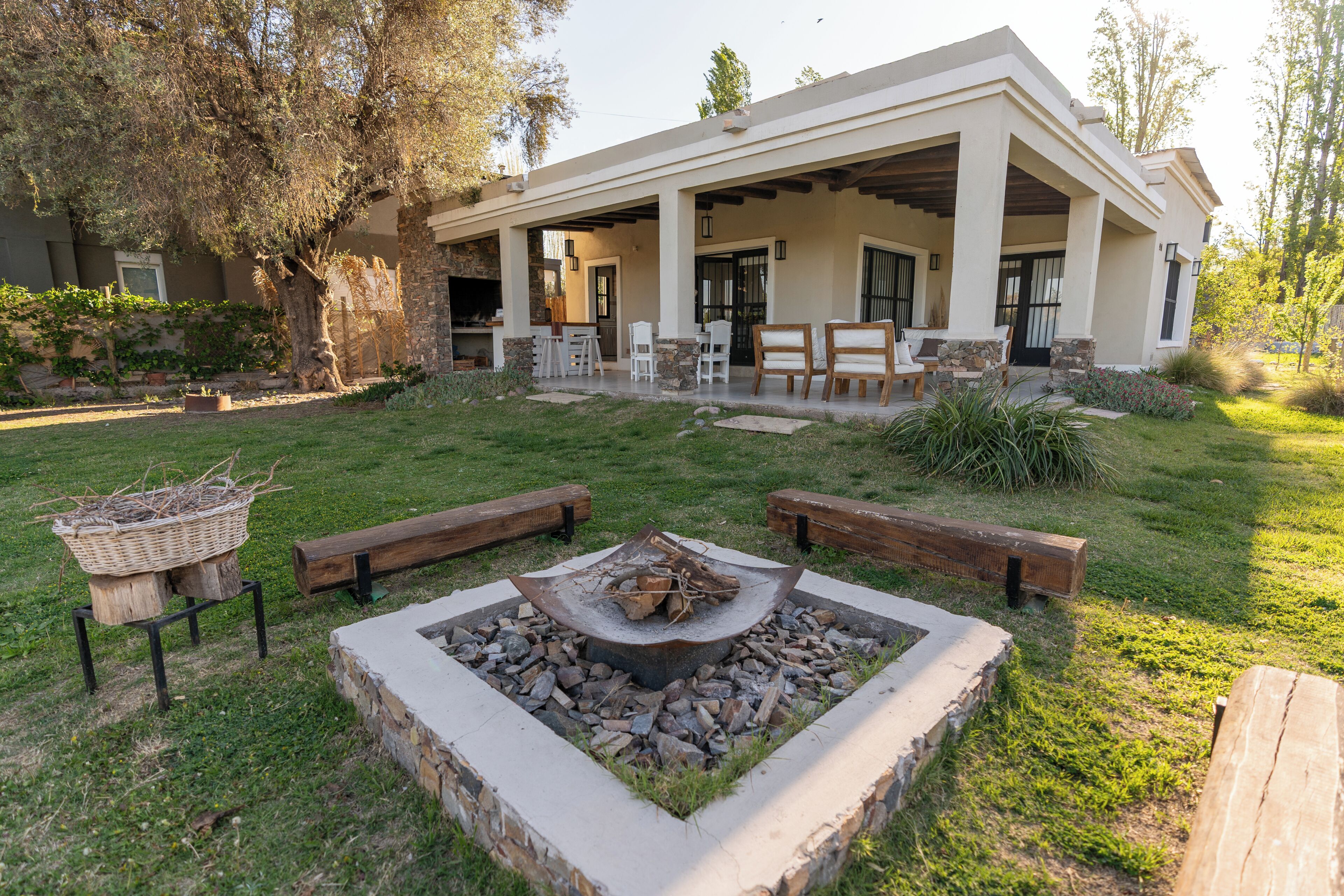 A modern house with a covered patio, outdoor seating, and a fire pit.
