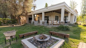 Une maison moderne dotée d’un patio couvert, d’un espace salon extérieur et d’un foyer.