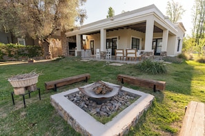 A modern house with a covered patio, outdoor seating, and a fire pit. - Casa Andina: Rustic Warmth, Fire Corner and Total Relaxation in Chacras (Luján de Cuyo)