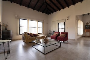 A spacious living room with a high ceiling, large windows, a glass coffee table, and two sofas. - Casa Andina: Rustic Warmth, Fire Corner and Total Relaxation in Chacras (Luján de Cuyo)