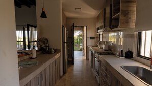 A modern kitchen with wooden cabinets, a stainless steel sink, and a view to the outside. - Casa Andina: Rustic Warmth, Fire Corner and Total Relaxation in Chacras (Luján de Cuyo)