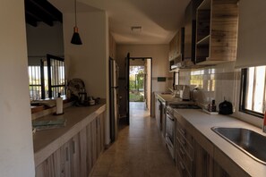 Cocina moderna con armarios de madera, un lavamanos de acero inoxidable y vistas al exterior.