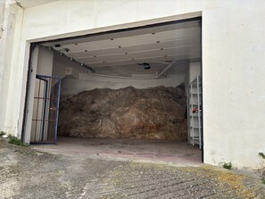 Eine Garage mit einer Betonwand, einem Metallgitter und einem Metallregal.
