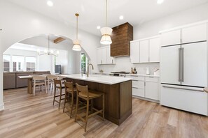 A modern kitchen with a central island, white cabinetry, and a large refrigerator. - Goodwin Glow - Walk to Lake Michigan & Pool (Union Pier)