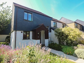 A two-story house with a dark roof, white walls, and a small front porch. - Stargazy (Falmouth)