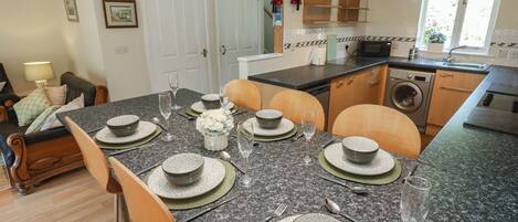 A dining area with a granite table, chairs, and a kitchen in the background.