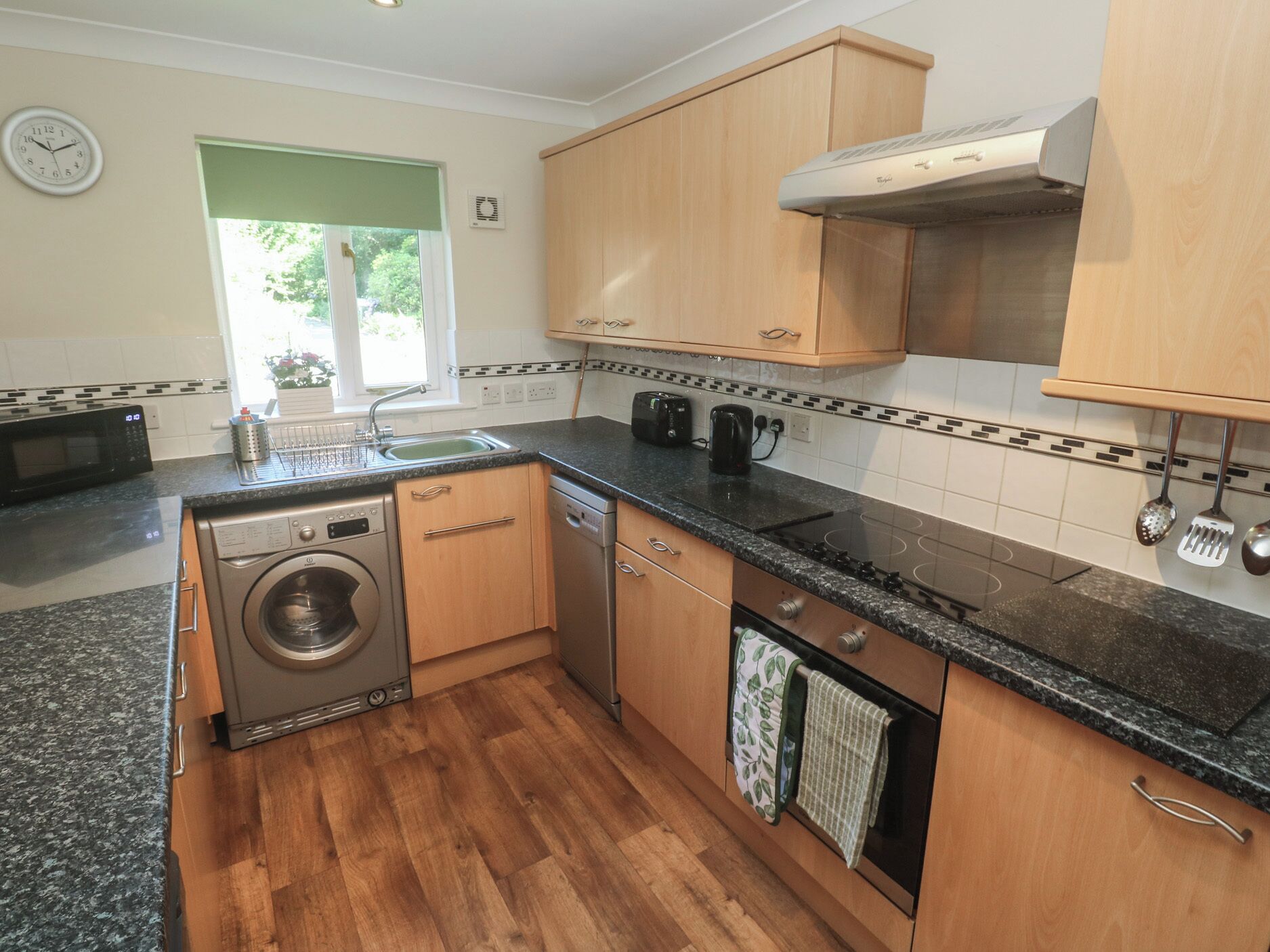 A modern kitchen with wooden cabinets, a built-in oven, a microwave, and a dishwasher.