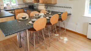 Una cocina moderna con armarios de madera, encimera de granito y comedor con cuatro sillas y una mesa dispuesta para dos comensales.