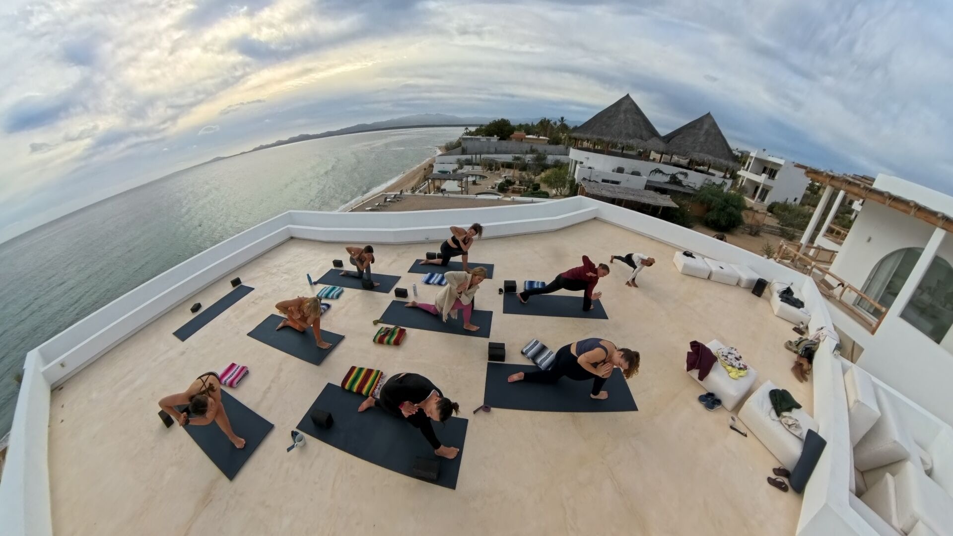 A rooftop yoga class with a view of the sea and a resort building.