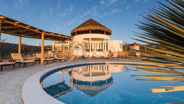 A pool with lounge chairs, a thatched-roof building, and a clear sky. - Casa Tara Retreat  (El Sargento)
