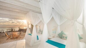 A beachside room with a bed, a table, and chairs, and a view of the ocean. - Casa Tara Retreat  (El Sargento)