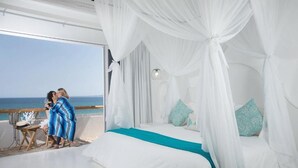 A bedroom with a bed, white curtains, and a view of the sea. - Casa Tara Retreat  (El Sargento)