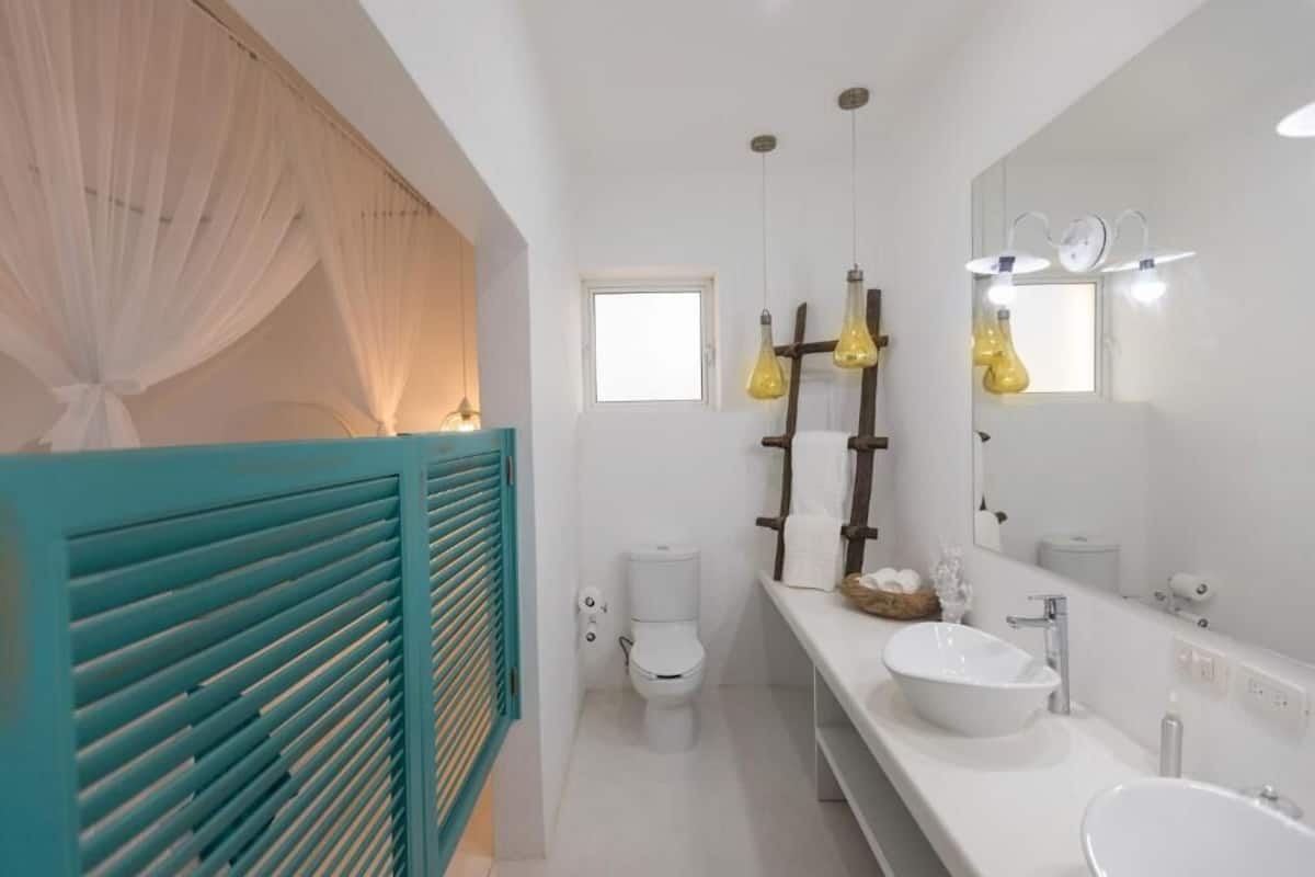 A bathroom with a white sink, a mirror, a toilet, and a window.