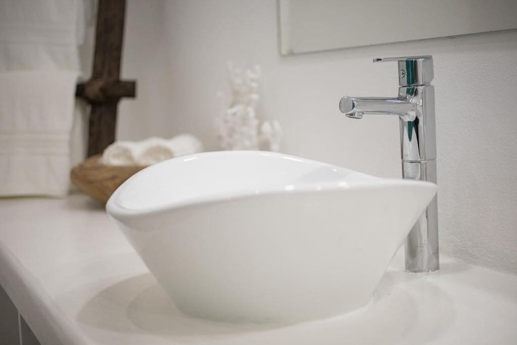 A white ceramic sink with a modern faucet on a white countertop.
