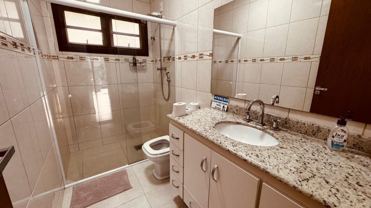 A bathroom with a shower, toilet, sink, and a mirror.