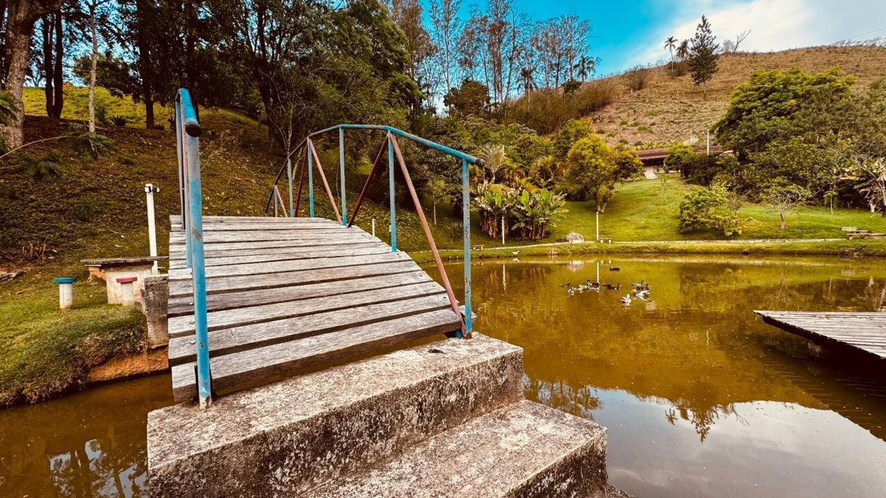 A wooden bridge over a pond with steps leading up to it, surrounded by greenery and trees.