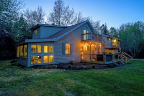 A two-story house with a balcony, large windows, and a deck.