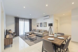 Ein modernes Wohnzimmer mit Sofa, Couchtisch, Esstisch und Stühlen.
