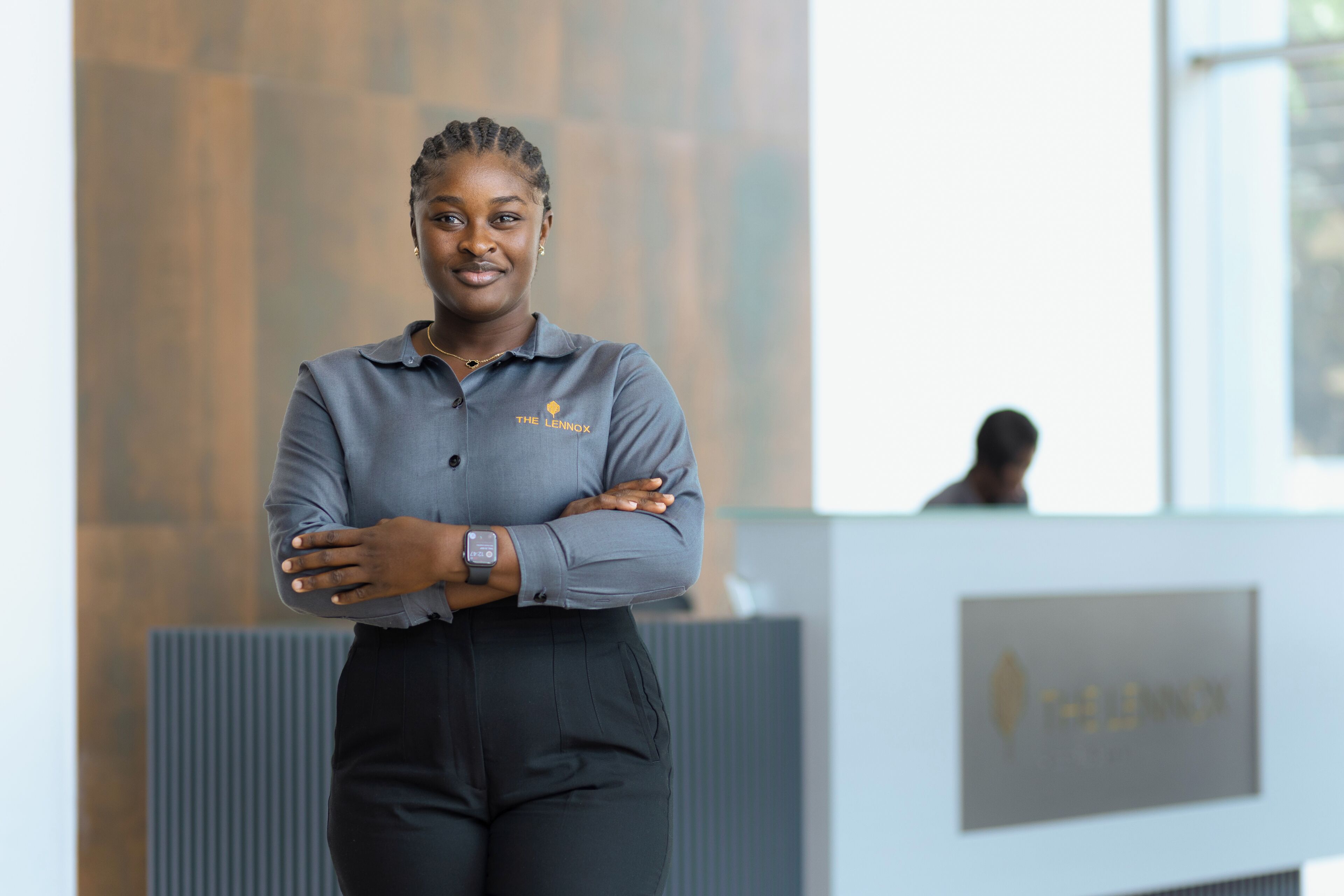 A person standing with crossed arms in a modern interior with a reception desk in the background.