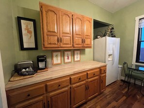 Eine Küche mit Holzschränken, einem Kühlschrank, einer Kaffeemaschine und gerahmten Bildern an der Wand.