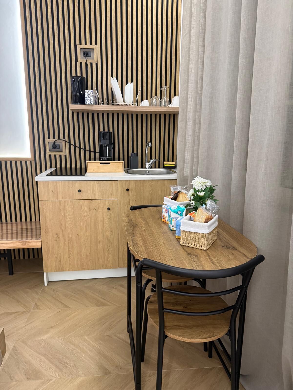 A compact kitchenette with a built-in coffee maker, a sink, and a small countertop.