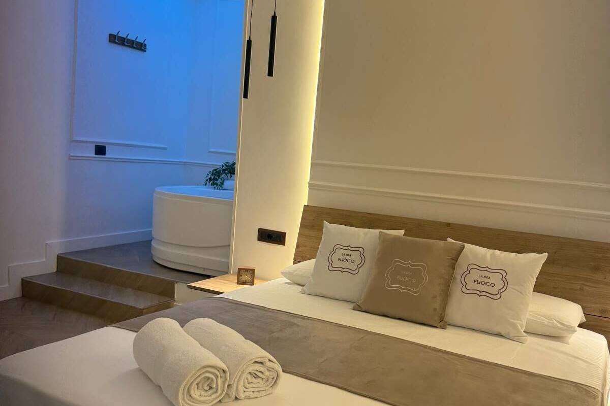 Une chambre à coucher moderne avec un lit, des oreillers et une serviette enroulée.