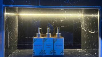 Un baño con encimera de mármol y tres productos Bagnoschioma: gel de ducha, champú y acondicionador.