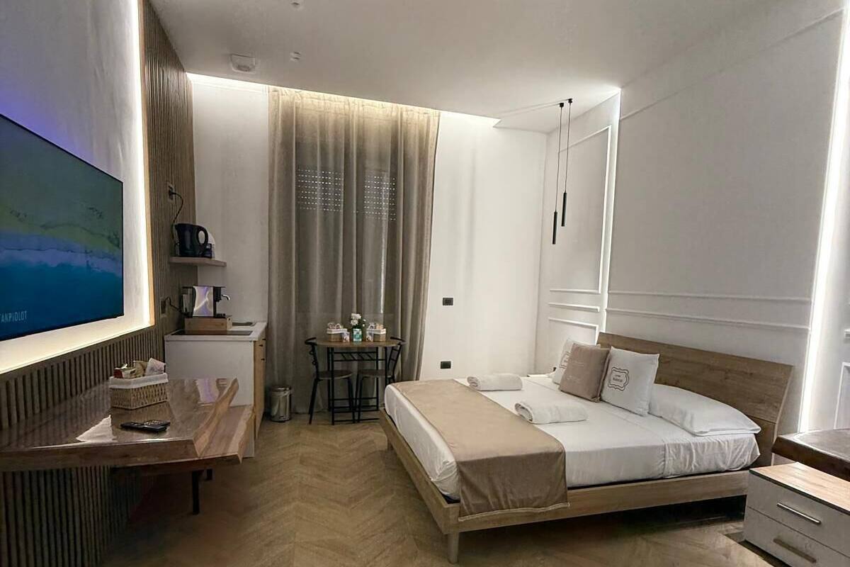 Une chambre d’hôtel moderne équipée d’un lit, d’un bureau, d’une télévision et d’une petite table avec une chaise.