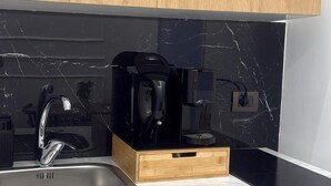 A kitchen with a black countertop, a stainless steel sink, and wooden cabinets. - Anthony Emanuele Fuoco (Torre del Greco)