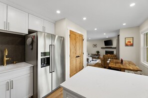 A modern kitchen with white cabinets, stainless steel appliances, and a wooden door. - Edwards Condo - near Shaw Center & Beaver Creek (Edwards)