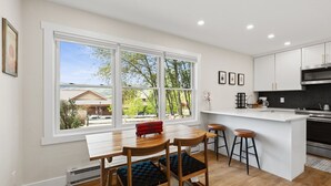 Eine moderne Küche mit großem Fenster, weißen Schränken und einer Kochinsel mit Sitzgelegenheiten.