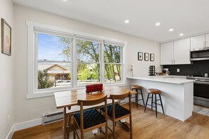 A modern kitchen with a large window, white cabinetry, and a central island with stools. - Edwards Condo - near Shaw Center & Beaver Creek (Edwards)