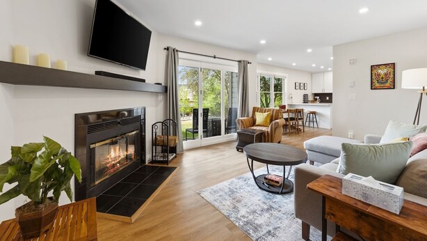 Ein modernes Wohnzimmer mit Kamin, Flachbildfernseher und Essbereich mit Tisch und Stühlen.