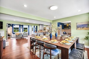A spacious dining area with a long wooden table set for a meal, surrounded by modern chairs.