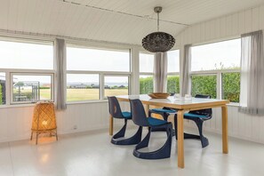 Zona pranzo con tavolo e sedie, ampie finestre e lampadario.