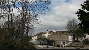 Et landlig hus med hvide vægge, skorsten og en lille veranda.