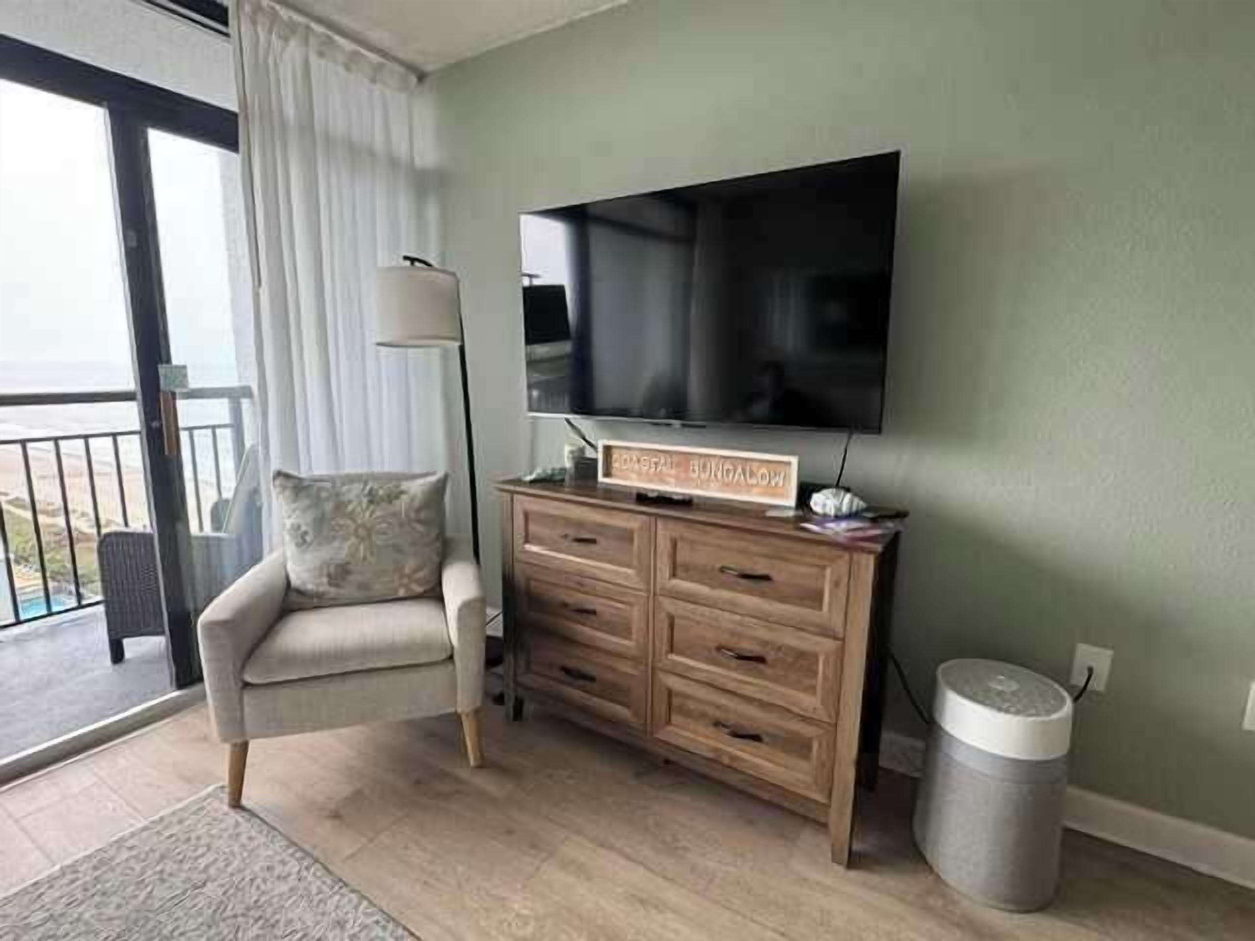 A room with a sofa, a TV, a wooden cabinet, and a trash can.
