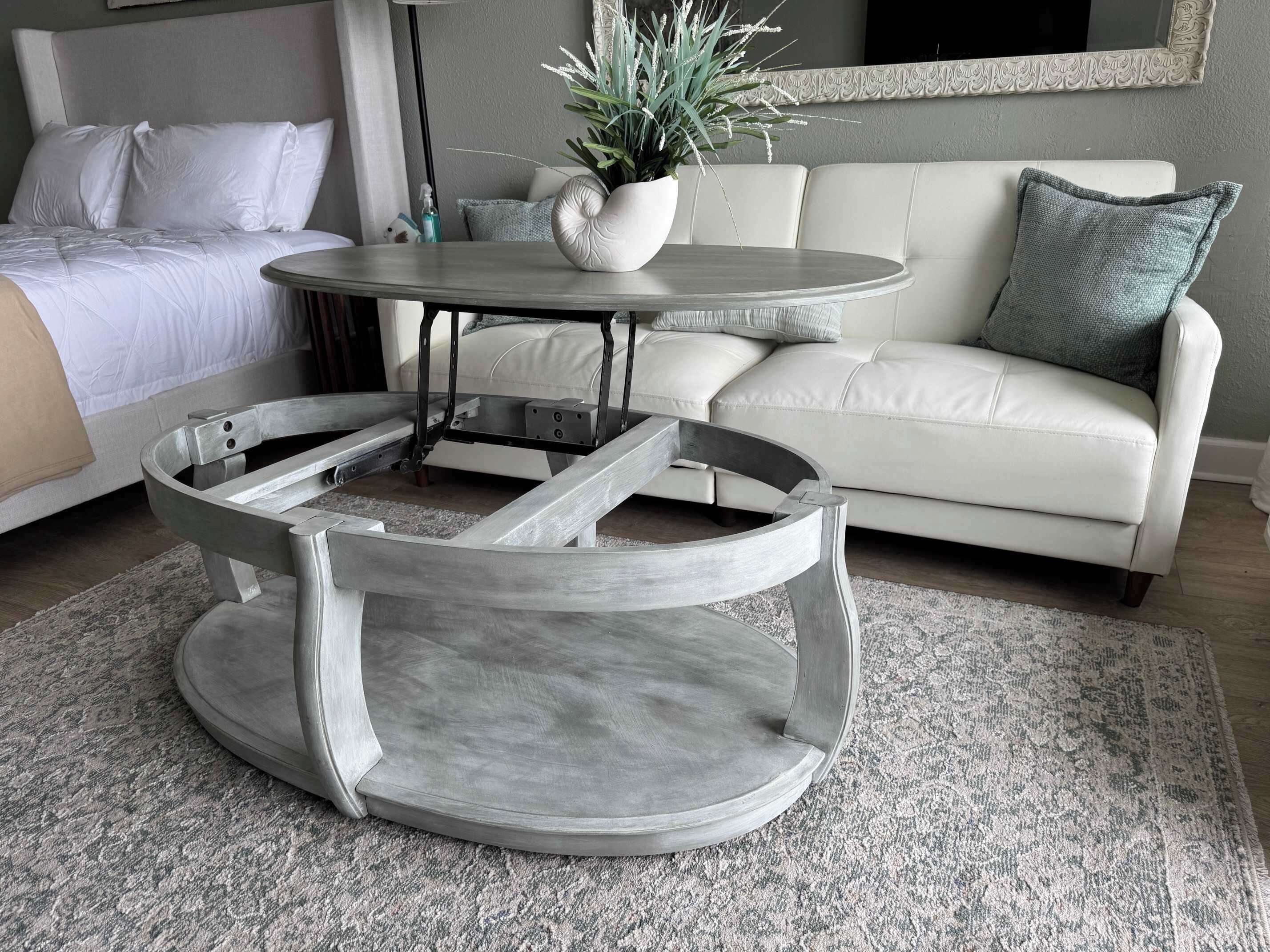 A modern living room with a round coffee table, a sofa, and a bed.