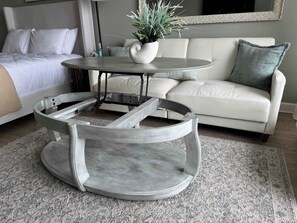 Ein modernes Wohnzimmer mit einem runden Couchtisch, einer Couch und einem Bett.