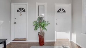 En gang med tre hvide døre, hver mærket med et nummer. En potteplante står i midten.