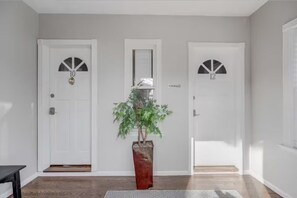 A hallway with three white doors, each marked with a number. A potted plant is placed in the center. - Cozy 3BR Medford l Minutes to Downtown lSleeps 6 (Medford)