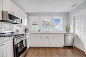 A modern kitchen with white cabinetry, a stainless steel stove, and a dishwasher. - Cozy 3BR Medford l Minutes to Downtown lSleeps 6 (Medford)