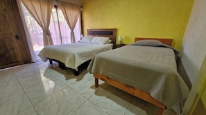 A room with two beds, a wooden headboard, a nightstand, and a window with curtains. - Eltoconar atacama (San Pedro de Atacama)