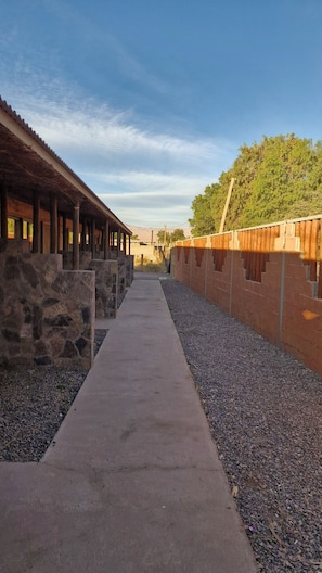 A pathway leading to a building with stone walls and a wooden roof. - Eltoconar atacama (San Pedro de Atacama)